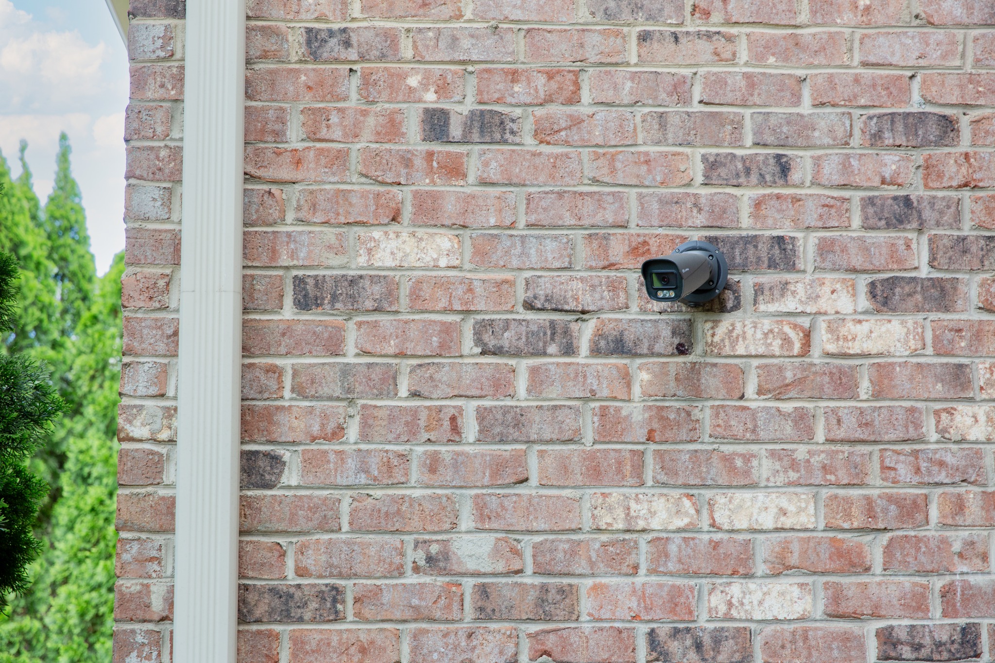 Discreet exterior surveillance camera mounted on a brick residence
